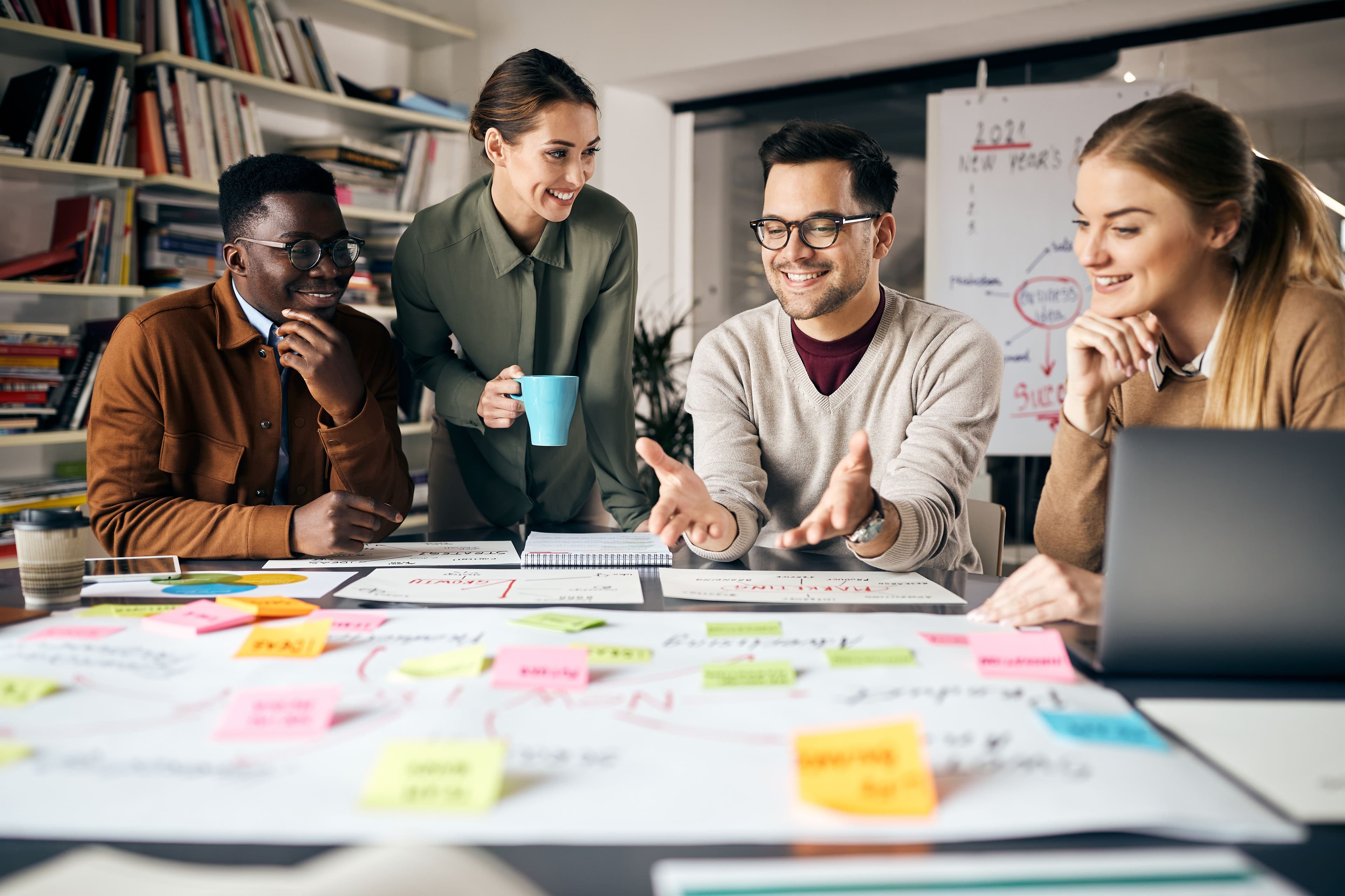 Flere personer sitter rundt et bord å ser på tankekart med mange ulike post it lapper på.